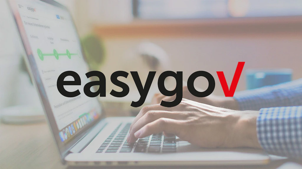 easygov Logo. Im Hintergrund ein Laptop mit zwei tippenden Händen.