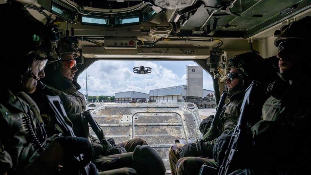 Soldaten im Inneren eines Militärfahrzeugs mit Blick nach aussen auf Drohne