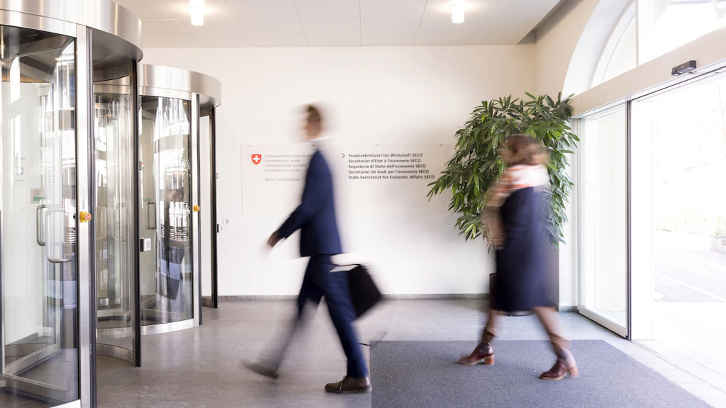 Zwei verschwommene Personen betreten den Eingangsbereich des SECO