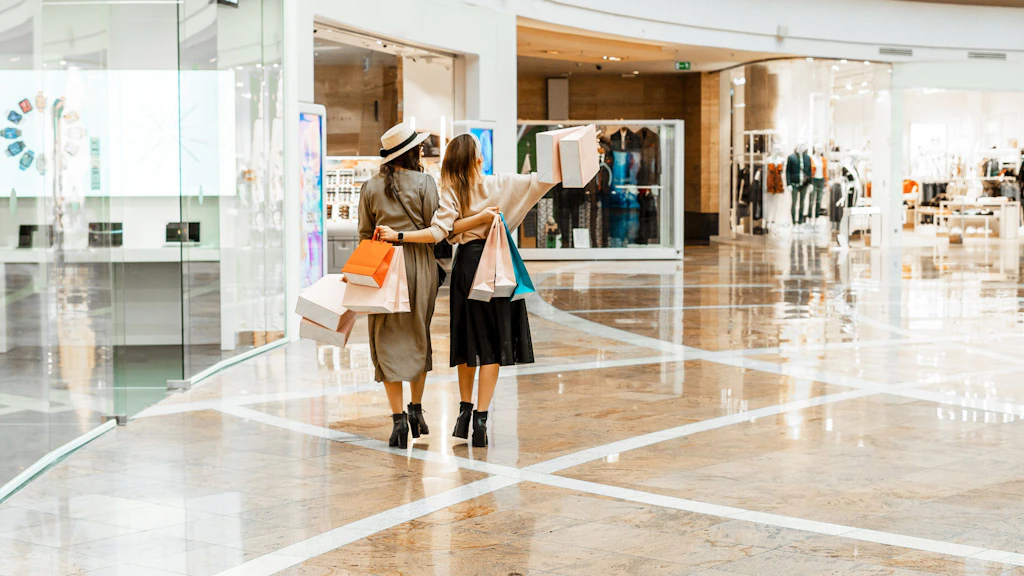 Deux jeunes femmes flânent le dimanche dans le centre commercial avec des sacs de shopping.