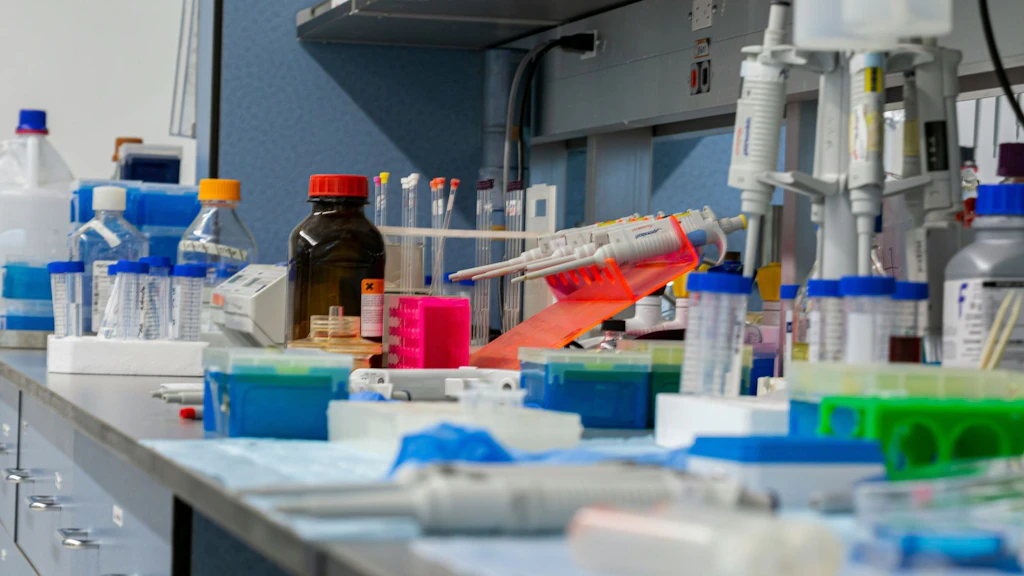 Chemielabor-Stillleben: Verschiedene Laborutensilien wie Glasgefässe, Reagenzgläser, Pipetten und Messgeräte stehen durcheinander auf einer Arbeitsfläche im Labor.