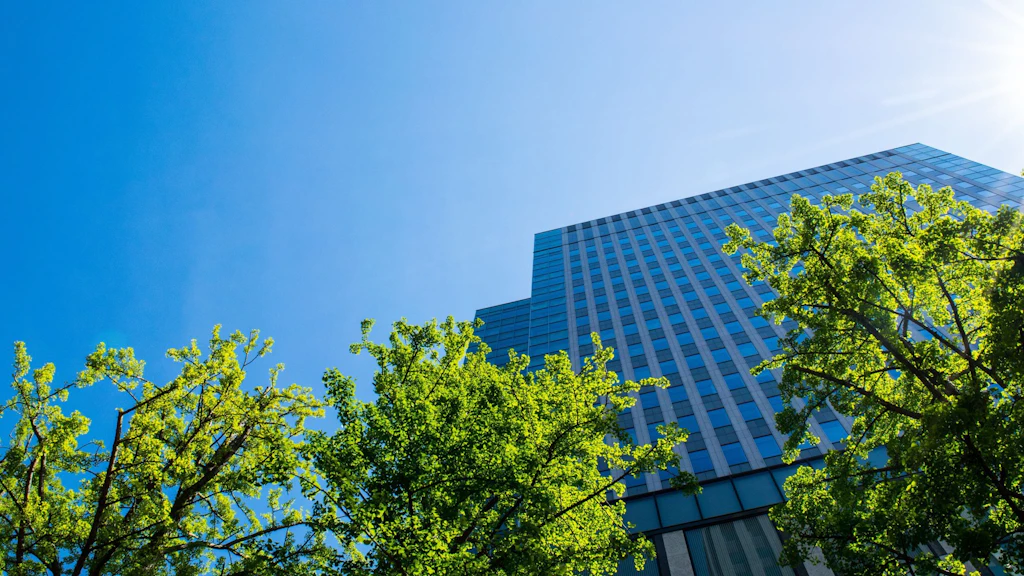 Des arbres verts devant un immeuble de bureaux bleu.