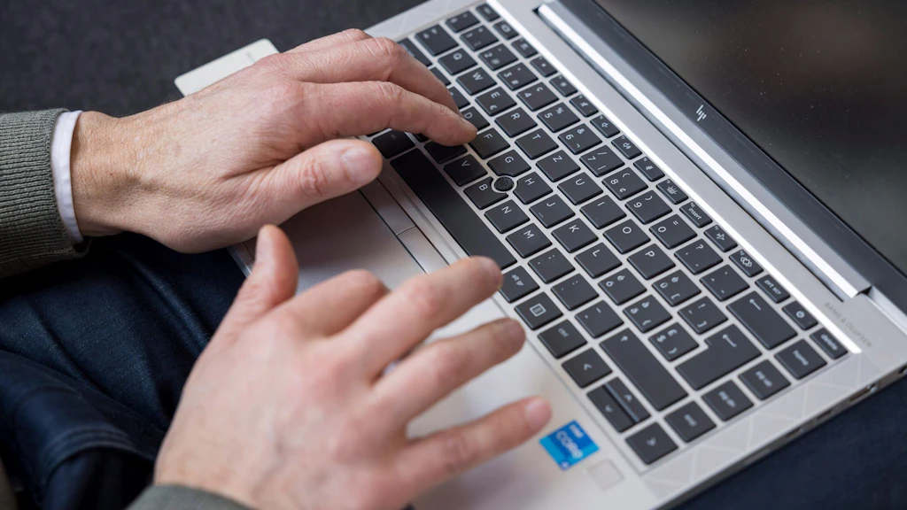 Hände tippen auf einem Laptop.