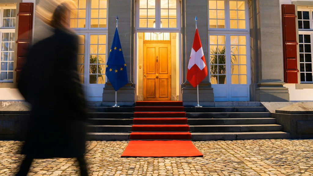 Ein Eingang zur Botschaft mit rotem Teppich und den Flaggen der EU und der Schweiz.