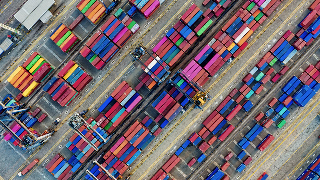Farbige Schiffscontainer aus der Vogelperspektive in einem Hafen.