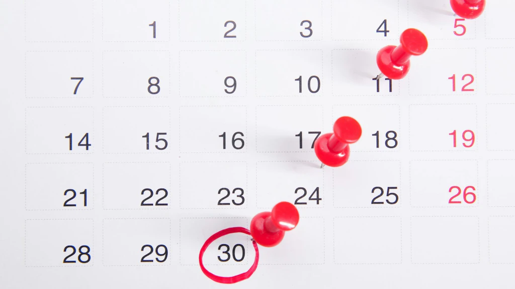 Kalenderblatt mit Datumszahlen und mehreren roten Reissnägeln. Das Datum 30 ist rot eingekreist und markiert.