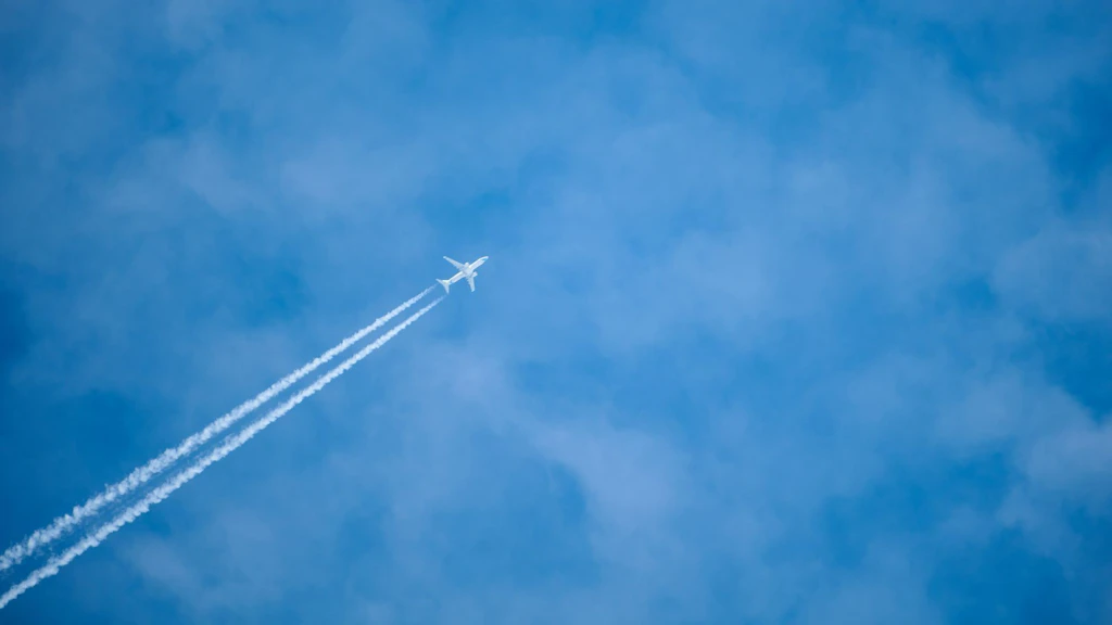 Ein Flugzeug am Himmel mit Kondensstreifen.