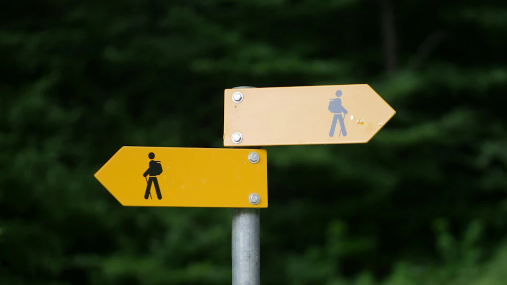 Wanderwegweise mit zwei Pfeilen, welche in gegensätzliche Richtungen zeigen.