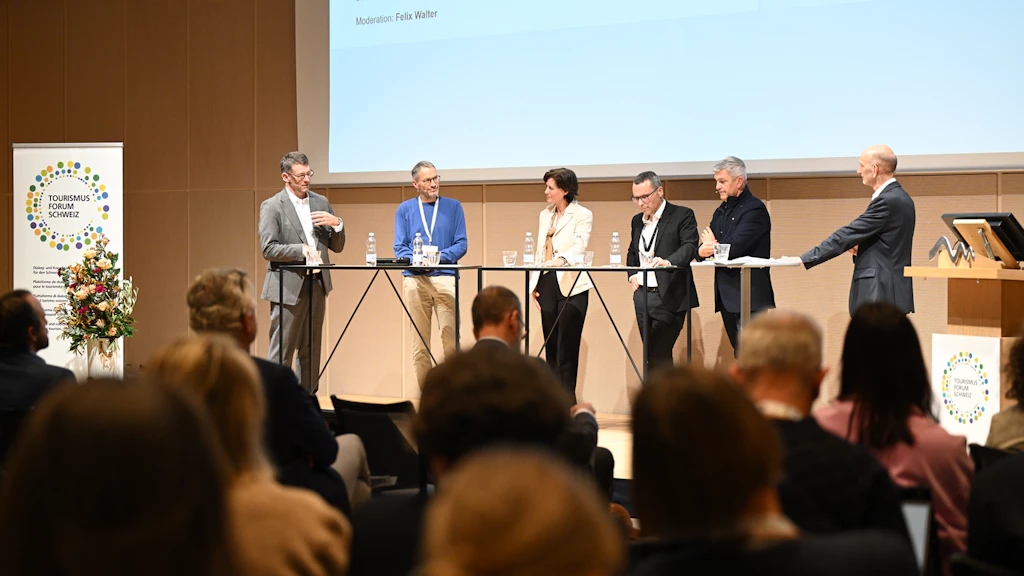 Sechs Personen diskutieren zusammen auf einer Bühne am Tourismum Forum Schweiz 2025