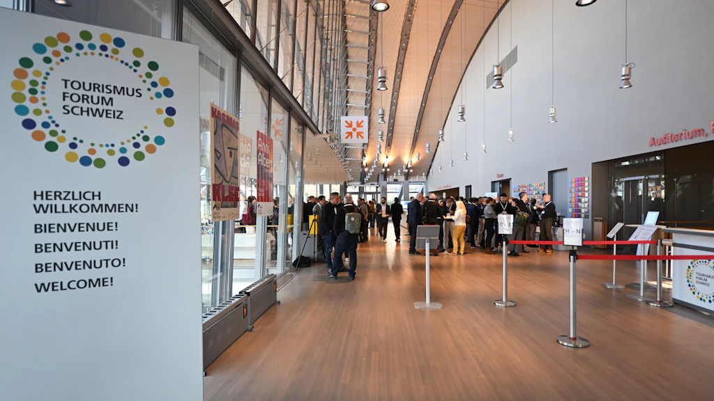 TFS Willkommensschild mit Blick auf das Foyer mit Teilnehmenden der Veranstaltung