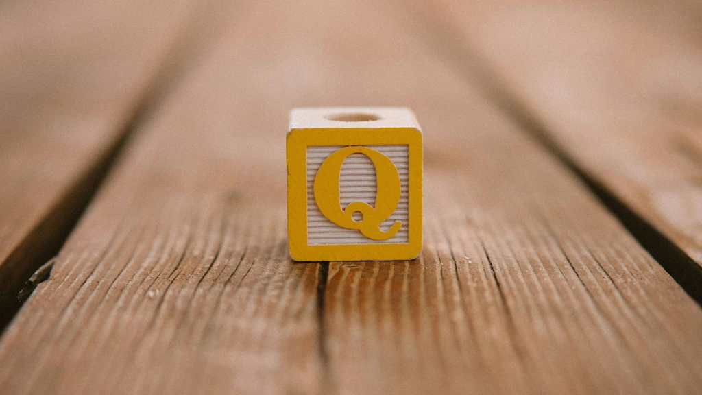 A cube with the letter Q on a wooden board