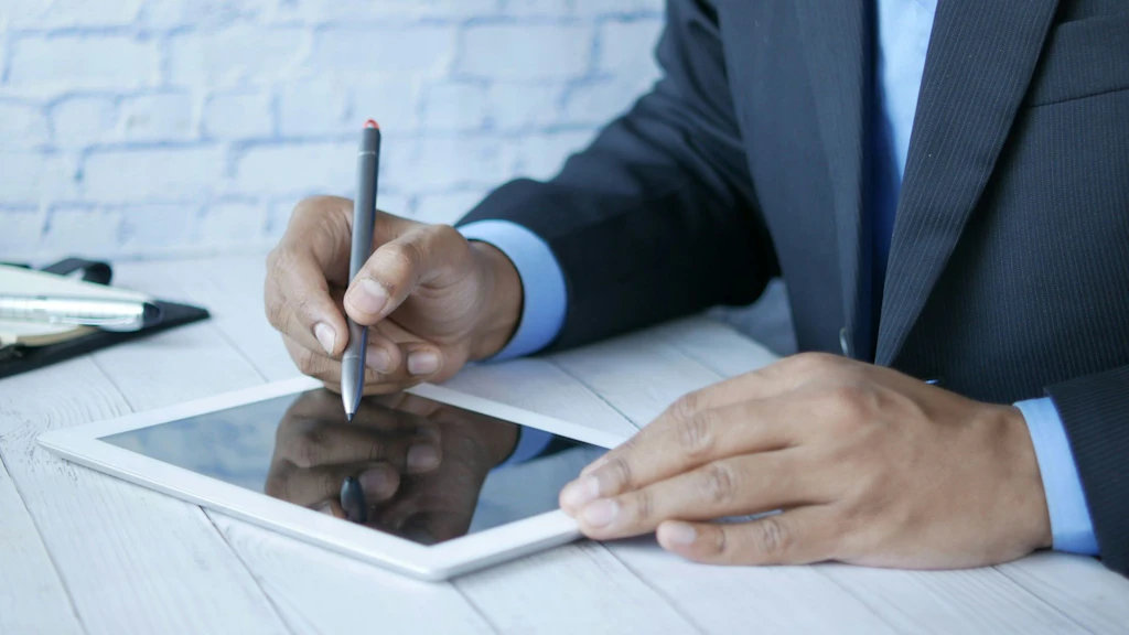A person's two hands provide a digital signature on a tablet