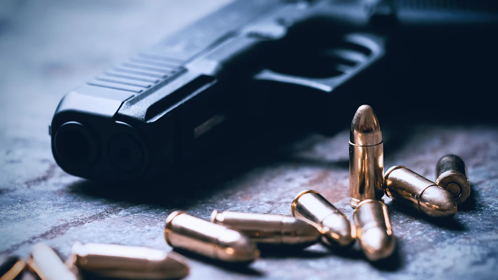 A table with a pistol and ammunition on it.