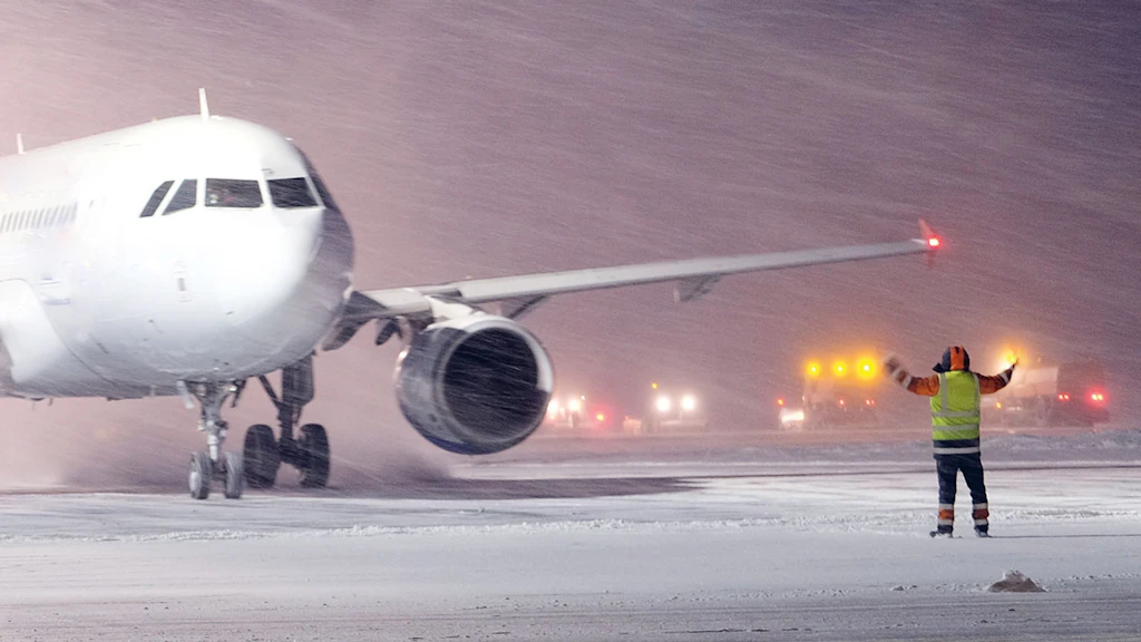 En hiver, un contrôleur aérien guide un avion sur la piste d'atterrissage.