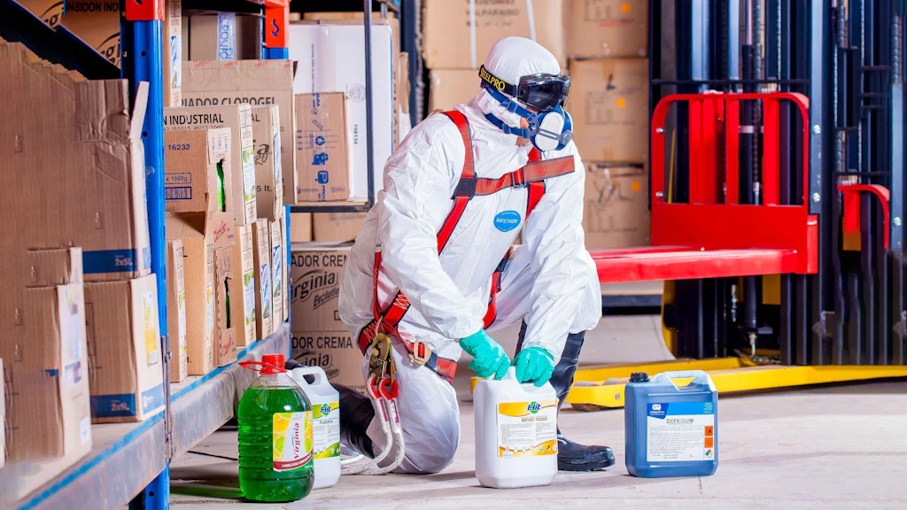 Un ouvrier en combinaison de protection manipule des liquides chimiques.