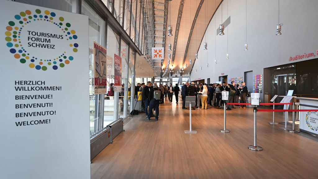 Panneau de bienvenue TFS donnant sur le foyer, avec des participants à l'événement