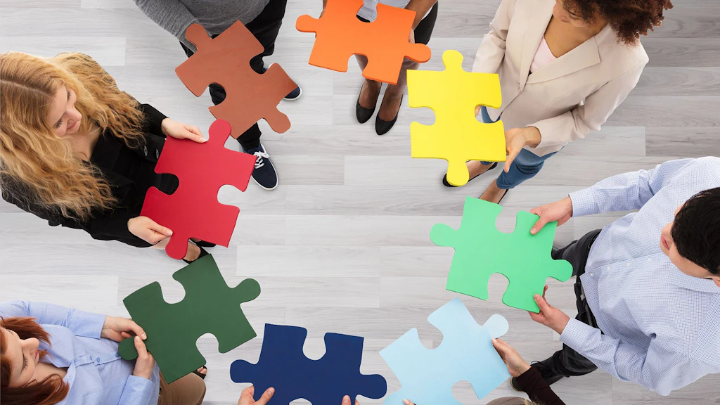 Un gruppo di giovani con in mano pezzi colorati di un puzzle