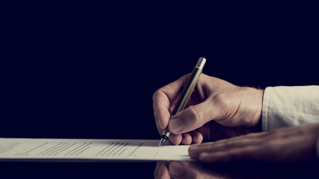Mano che tiene una penna e firma un documento